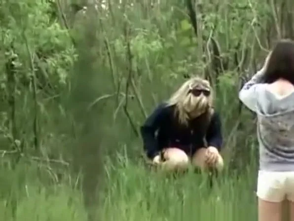 Woman and friend peeing outdoors