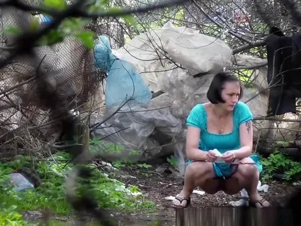Woman lifts her blue dress to pee