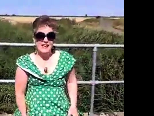 Flashing in green dress and white stilettos