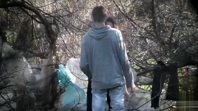 Caring boyfriend covers up girl peeing in the shrub